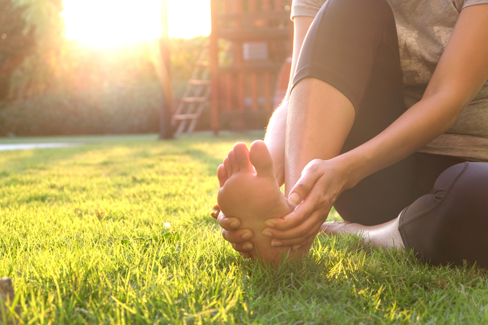 Woman holding the front of her foot near dress shoes due to toe discomfort.