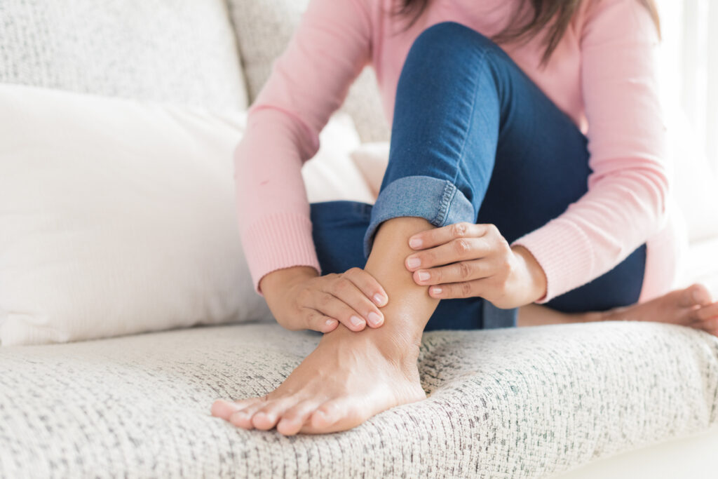Woman holding her ankle while experiencing persistent ankle pain before evaluation for ankle arthroscopy